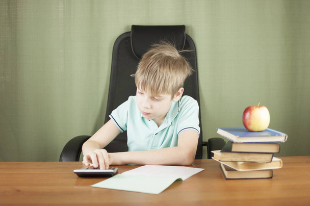 Rapaz da escola inteligente sentado à mesa com muitos livros e maçã vermelha. Conceito de educação
.  - Foto, Imagem