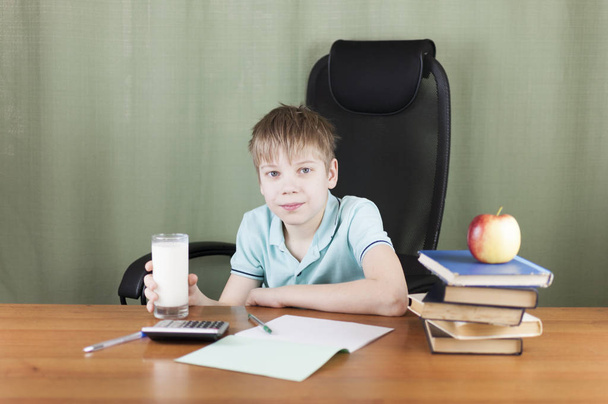 Smart school boy sitting at the table with many books and red apple. Concept of education.  - Photo, Image