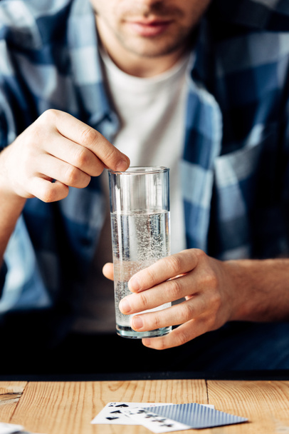 selective focus of man suffering from hangover holding aspirin and glass of water in hands - Фото, зображення