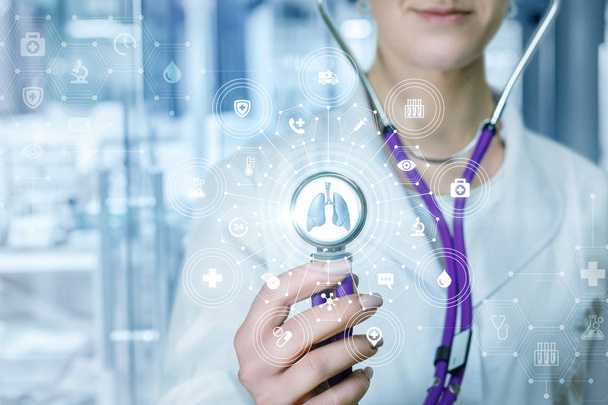 A closeup of doctor touching composite medical service system of icons and symbols with lungs model with stethoscope at the blurred hospital background. The concept of innovative approach in medicine. - Photo, image