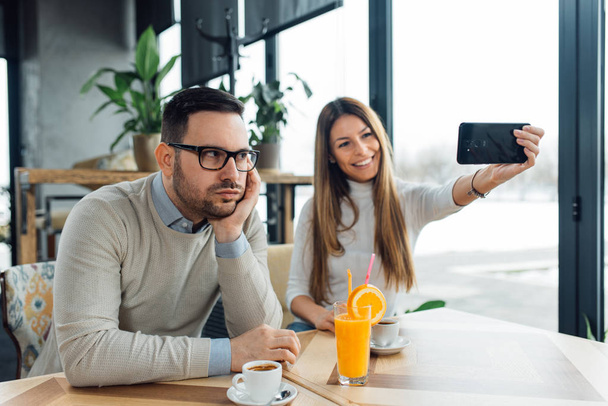 Young woman taking selfie and ignoring her boyfriend - Photo, Image
