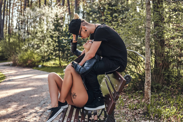 Paar verliefd knuffelen zittend op een bankje, samen genieten in een mooie zomerse park - Foto, afbeelding