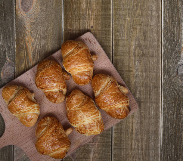 freshly baked homemade croissants with golden crust on a brown rustic wooden table. top view. space for text - Photo, Image