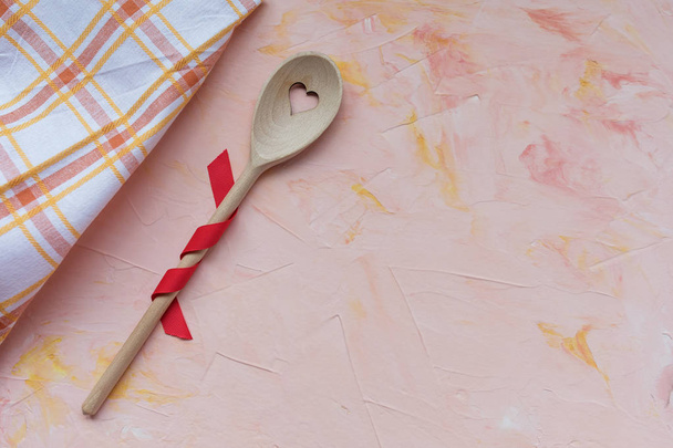 Stirring spoon and kitchen towel on a pink background . Spring holidays cooking and celebration concept. Top view, flat lay, copy space. - Photo, Image