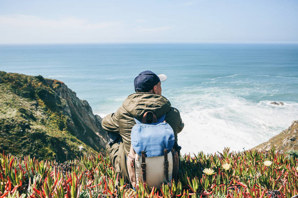 Ein Tourist mit Rucksack genießt an einem Frühlingstag einen schönen Blick auf den Atlantik - Foto, Bild