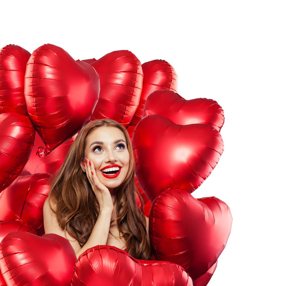Happy surprised woman with red balloons isolated on white background. Surprised girl with red lips makeup smiling and looking up. Surprise, gifts and Valentine's day concept isolated over white - Zdjęcie, obraz