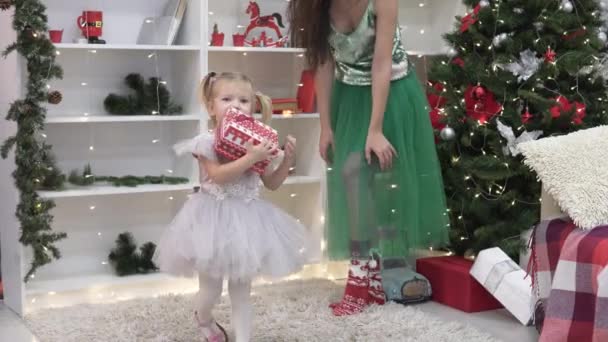 schöne elegante Frau macht einem kleinen Mädchen ein Neujahrsgeschenk - Filmmaterial, Video