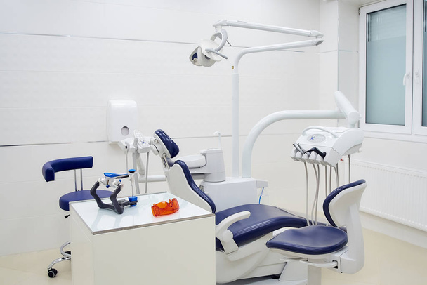 Нове стоматологічне крісло з біло-блакитними меблями. Стоматологічний офіс
 - Фото, зображення