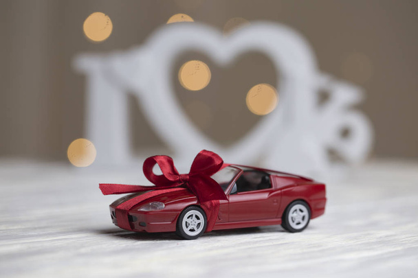 toy car with a bow on the background of the word love. toy car with gift ribbon - Photo, image