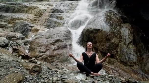 Mulher praticando ioga na cachoeira com fones de ouvido
 - Filmagem, Vídeo