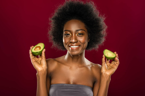 Positive nice woman holding two avocado halves - 写真・画像