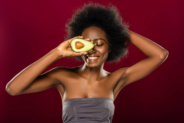 Delighted afro American woman enjoying eating avocados - Fotografie, Obrázek