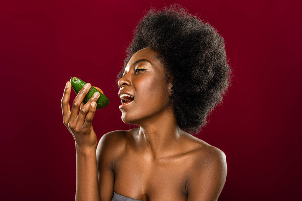 Beautiful afro American woman eating an avocado - Foto, Imagen