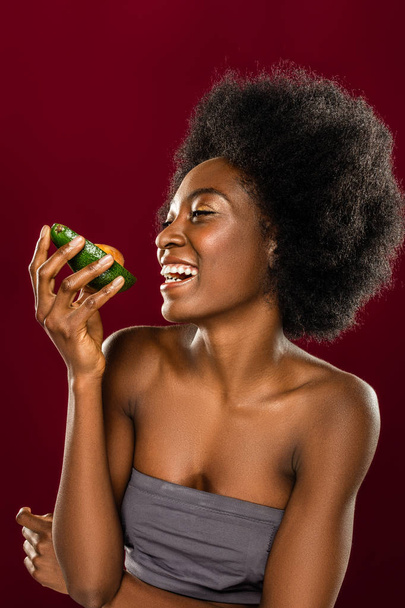 Positive happy woman standing with an avocado piece - Foto, Imagen