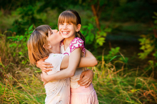 Dvě rozkošné malé sestřičky směje a objímání na slunečný den v létě parku - Fotografie, Obrázek