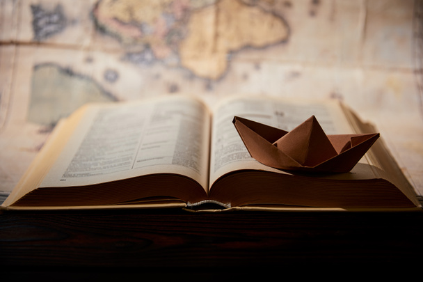 Selective focus of paper boat, book and map on table - Photo, Image