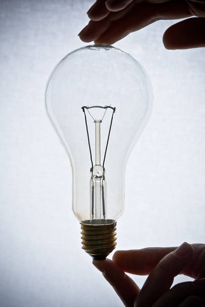 Glühbirne mit Händen auf weißem Hintergrund gehalten - Foto, Bild