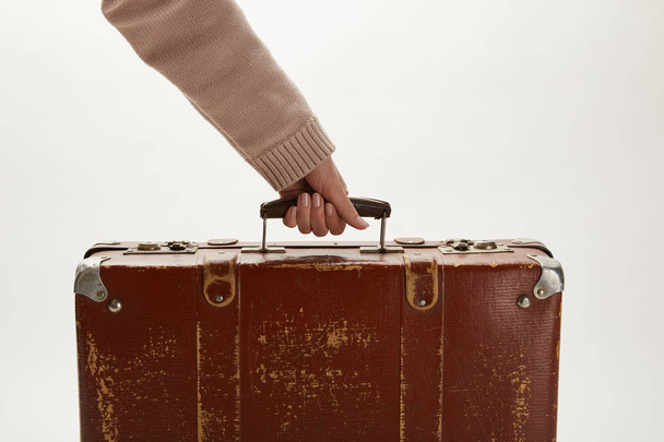 Partial view of woman holding brown suitcase isolated on grey - Foto, Bild
