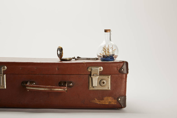 nave giocattolo in bottiglia di vetro e bussola su valigia marrone vintage con spazio copia
  - Foto, immagini