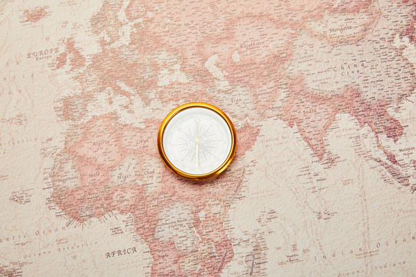 top view of golden compass on vintage world map - Φωτογραφία, εικόνα