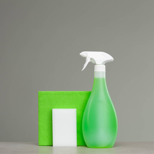 Cleaning green spray bottle with plastic dispenser, sponge and cloth for dust  on grey background. Cleaning tools. - Foto, Imagen