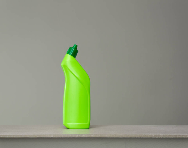 Green bottle of sanitary ware cleaner on grey background. - Fotoğraf, Görsel