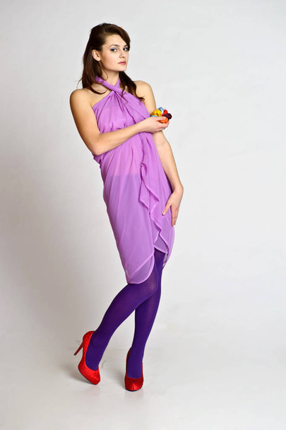 beautiful brunette girl in purple dress with skeins of wool on a white studio background - Fotografie, Obrázek