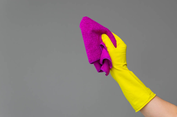 A hand in a rubber glove holds a bright microfiber duster on a neutral background. Concept of bright spring, spring cleaning. - Foto, immagini