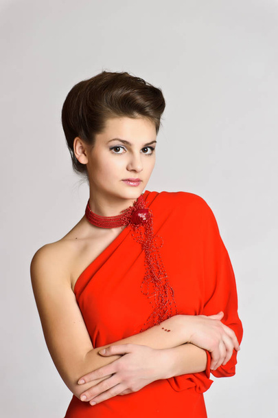 beautiful young brunette in red with a necklace on her neck on a white studio background - Foto, Imagem