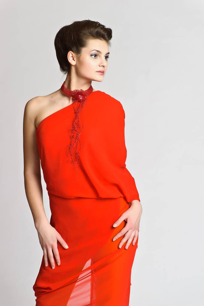 beautiful young brunette in red with a necklace on her neck on a white studio background - Foto, imagen