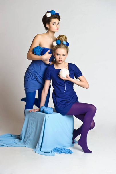 two girls in blue with balls of wool in their hands and in their hair, fashion - Fotó, kép