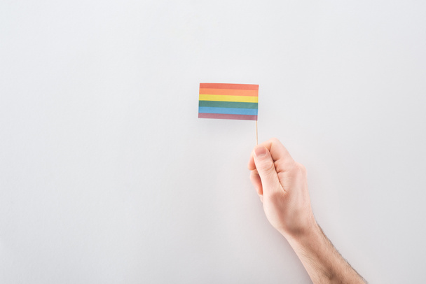 vista parcial de la mano masculina con bandera de arco iris de papel sobre fondo gris, concepto lgbt
 - Foto, imagen