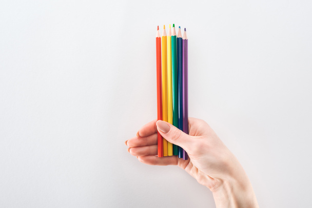 Teilansicht der weiblichen Hand mit regenbogenfarbenen Bleistiften isoliert auf grau, lgbt-Konzept - Foto, Bild