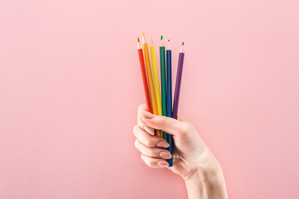 Teilansicht weiblicher Hand mit regenbogenfarbenen Bleistiften auf rosa Hintergrund, lgbt-Konzept - Foto, Bild