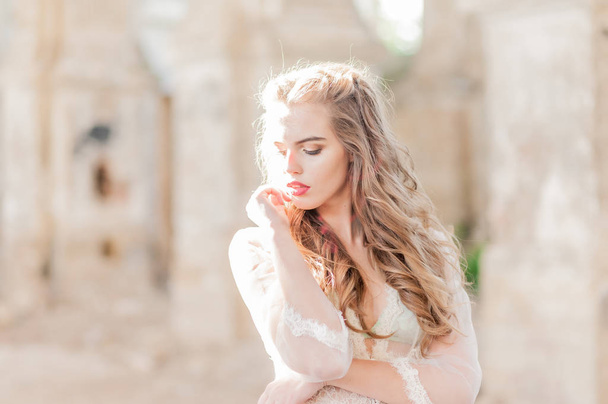 Retrato de una joven novia en un tocador de encaje blanco con el pelo oscuro ondulado - Foto, Imagen