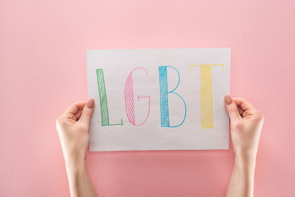 részleges kilátás nyílik tartó fehér papír, kézzel írt "LMBT" rövidítése, a rózsaszín háttér női - Fotó, kép