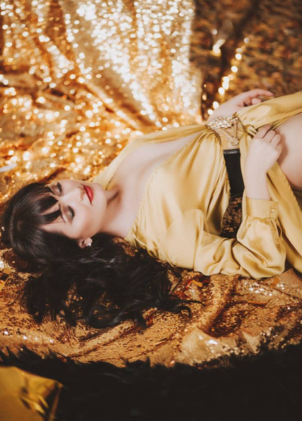 Arany ruhában pózol a gyönyörű fiatal nő - Fotó, kép