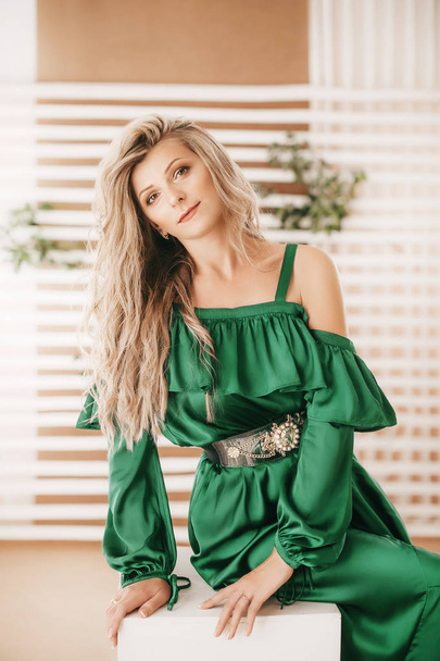 Portrait of beautiful young blonde woman with makeup in green dress - Photo, image