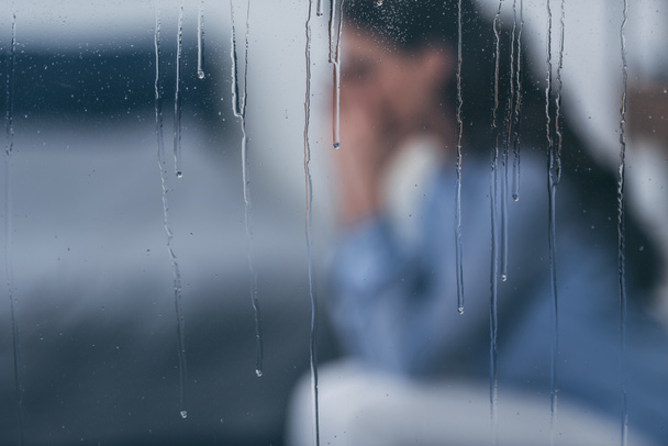 Selektywny fokus krople deszczu na windows z smutny kobieta siedzi na tle - Zdjęcie, obraz