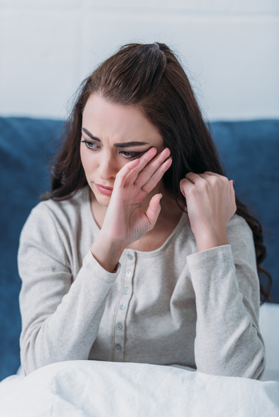 καταθλιπτική γυναίκα κλαίει και σκουπίζοντας τα δάκρυα ξαπλωμένοι στο κρεβάτι στο σπίτι - Φωτογραφία, εικόνα