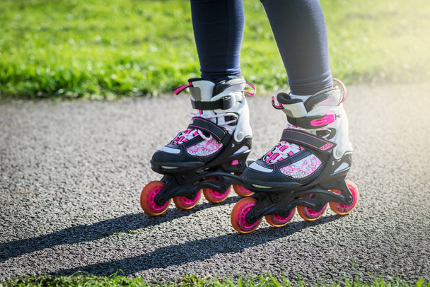 Teenage girl is skating on roller blades in the park  - 写真・画像