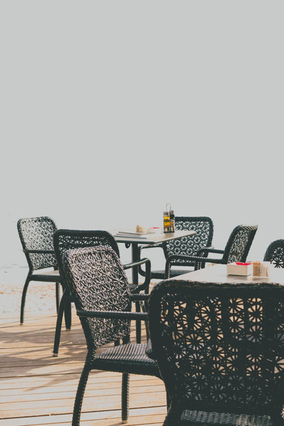 Плетеные стулья у пустых открытых столов ресторана на морском курорте летом
 - Фото, изображение
