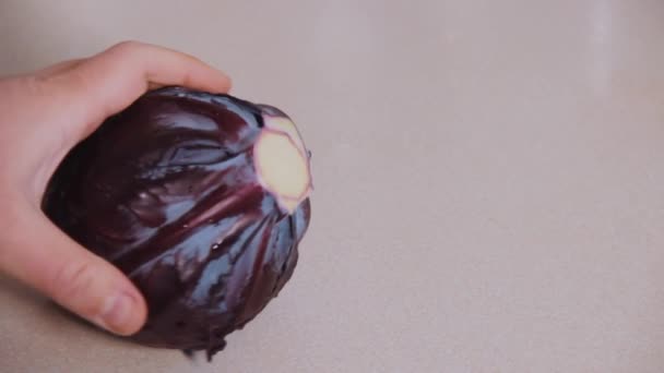 A head of red cabbage is rotated by hand on a beige-colored kitchen table. Healthy food. Vegetable diet. Vegetarianism. Vegetarian checks for freshness and examines whole vegetable before buying - Imágenes, Vídeo