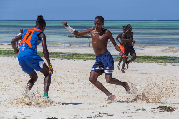2018.02.21, Kiwengwa, Tanzania. Travel around Tanzania. A group of an attractive African men playing football on the beach on background of blue sky and ocean. Entertainment in Zanzibar. - Foto, afbeelding