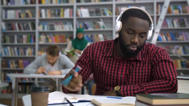 Dark-skinned student studying with book in library - Footage, Video