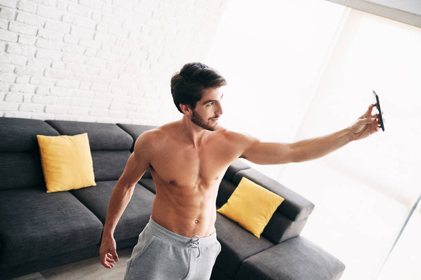 Hombre haciendo ejercicio en casa tomando foto selfie con el teléfono
 - Foto, imagen