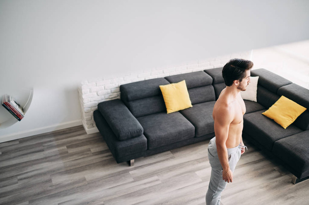 Ενήλικα άνδρα κατάρτισης μυς στο σπίτι ανάπαυσης μεταξύ των ασκήσεων - Φωτογραφία, εικόνα