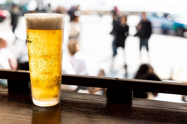 Склянка золотистого холодного пива на лічильнику, що виходить на вулицю в ресторані
 - Фото, зображення