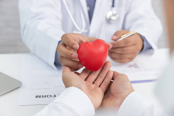 Terveydenhuolto ja lääketieteellinen käsite, lääkäri, jolla on sydänpallo ja selittää sydänsairauksien oireita ja lääketieteellistä hoitoa potilaalle sairaalassa
 - Valokuva, kuva