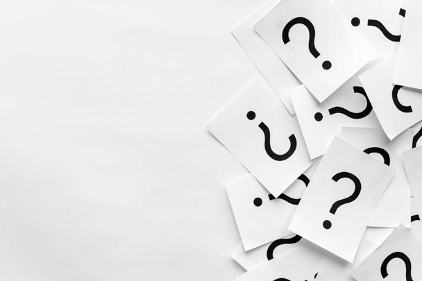 Pile of question marks printed on white cards forming a side border over a white background with copy space in a conceptual image - Photo, Image